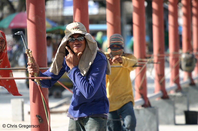 Photo of Construction Worker Holding an Acetylene Metal Cutter with Another Worker at the Background(5279)