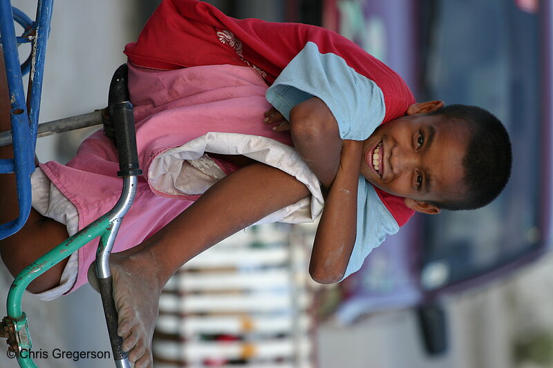 Photo of Image of a Smiling Street Boy on a Bicycle in Front of a Red Car with Dirty Feet(5286)